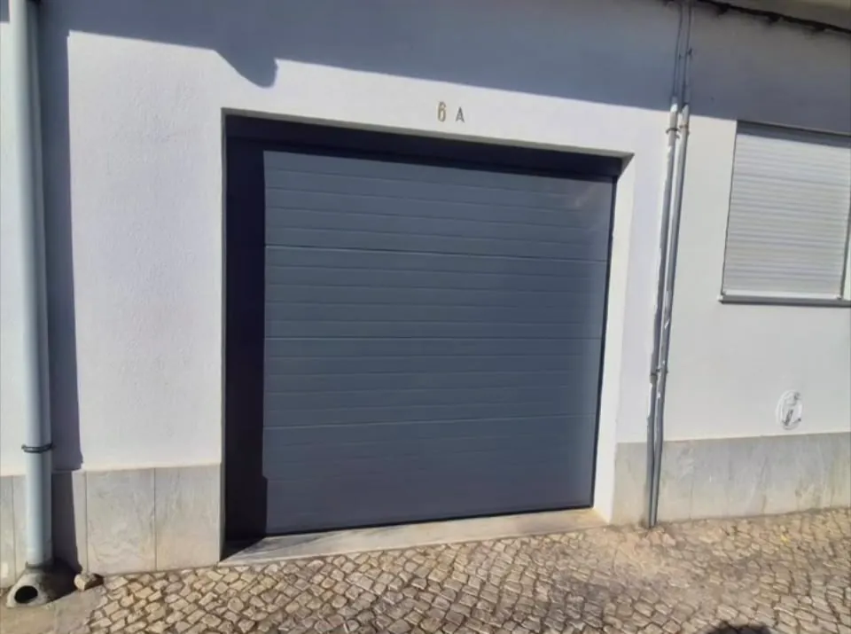 Portão seccionado cinzento instalado numa garagem